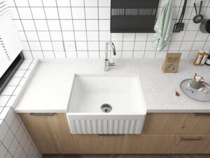 Modern farmhouse-style apron front kitchen sink with white quartz countertop and tile backsplash.