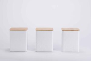 White tea, coffee, and sugar canisters with embossed diamond pattern and bamboo lids on a kitchen countertop