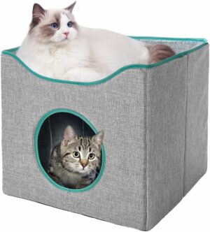 Two cats in a grey fabric foldable cat cube house, one resting on top and one peeking from inside through a round opening.