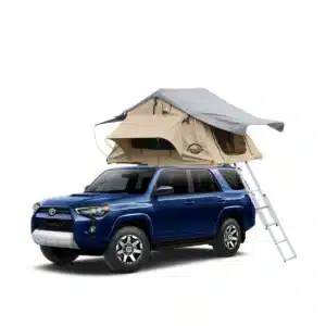 A dark blue Toyota 4Runner SUV with a light brown and grey roof top tent mounted on its roof rack, with a silver ladder extending to the ground.