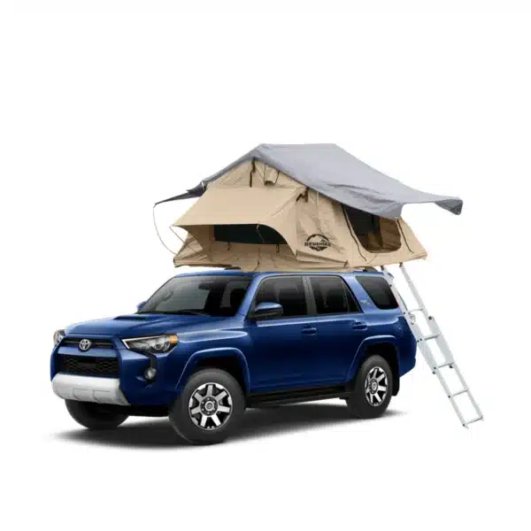 A dark blue Toyota 4Runner SUV with a light brown and grey roof top tent mounted on its roof rack, with a silver ladder extending to the ground.